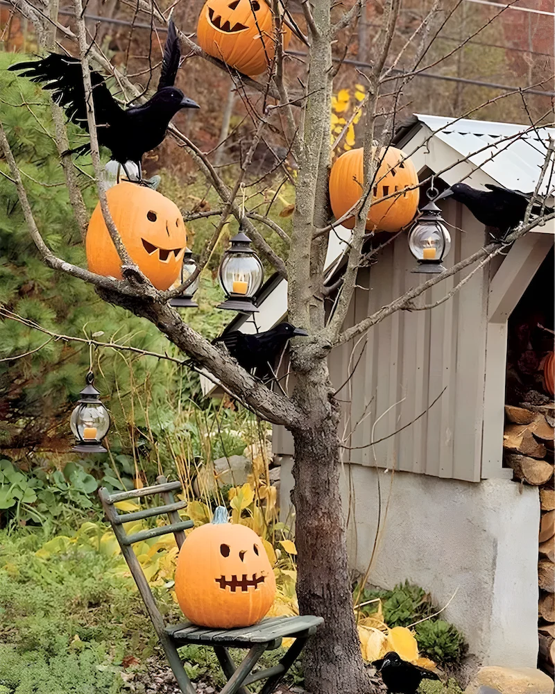 arbre du jardin décoré de citrouilles sculptées, lanternes suspendues et corbeaux noirs