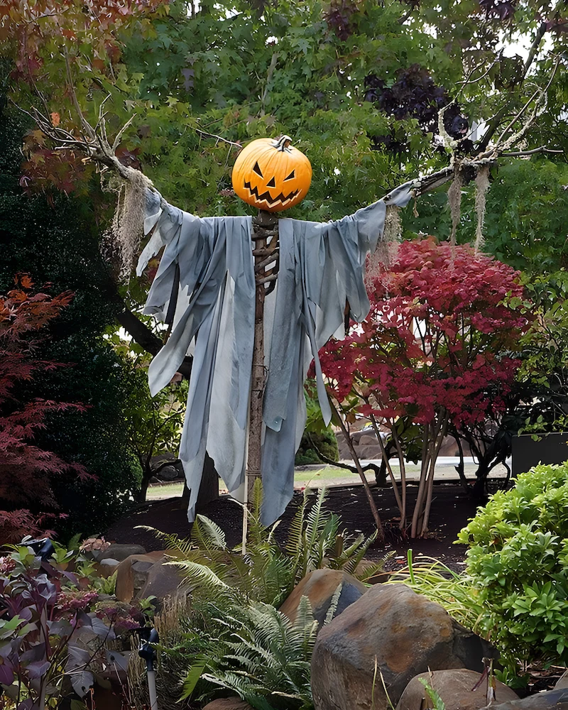 épouvantail d'Halloween à tête de citrouille vêtu de lambeaux de tissu gris dans un massif