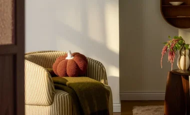 Fauteuil rayé avec coussin citrouille bouclette et plaid vert pour une déco d'automne cosy