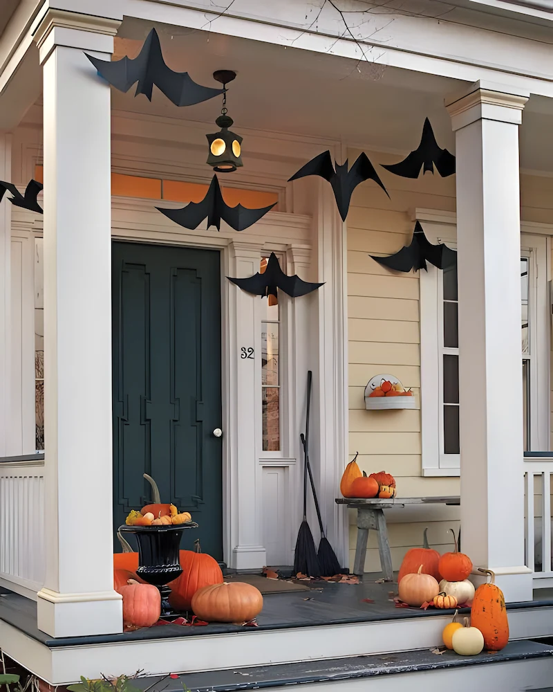 porche d'Halloween avec grandes chauves-souris noires suspendues, balais et citrouilles