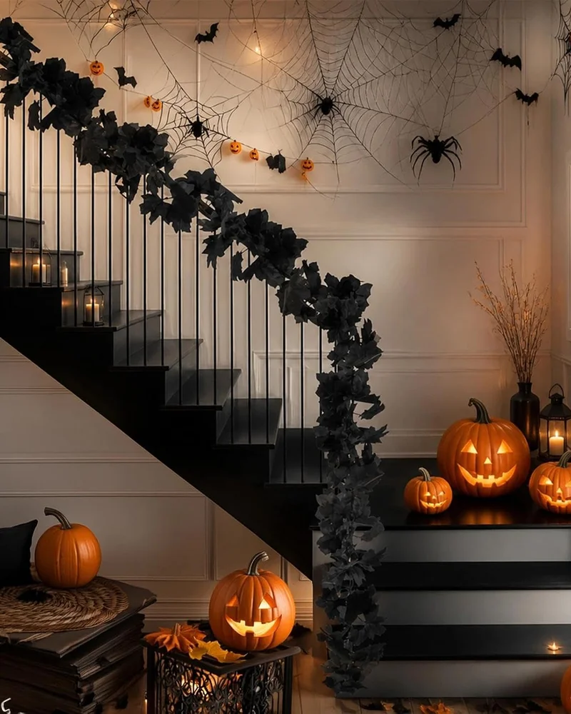 Guirlande de feuilles noires sur la rampe d'un escalier décoré de citrouilles et toiles d'araignée