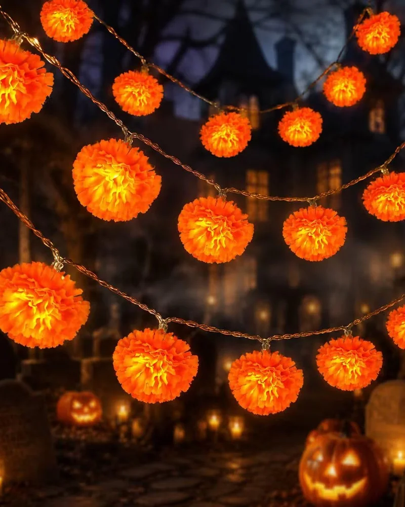 Guirlande lumineuse de pompons orange façon œillets d'Inde devant un décor de cimetière d'Halloween