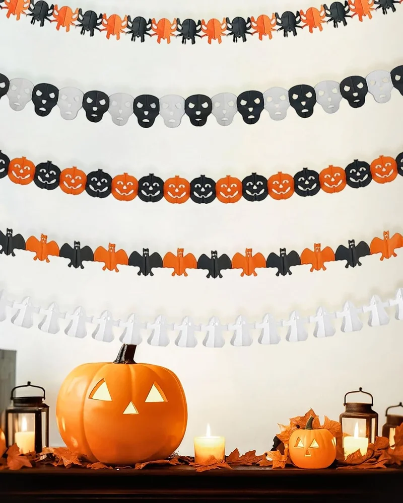 Guirlandes en papier Halloween citrouilles, têtes de mort, chauves-souris et fantômes au-dessus d'une console