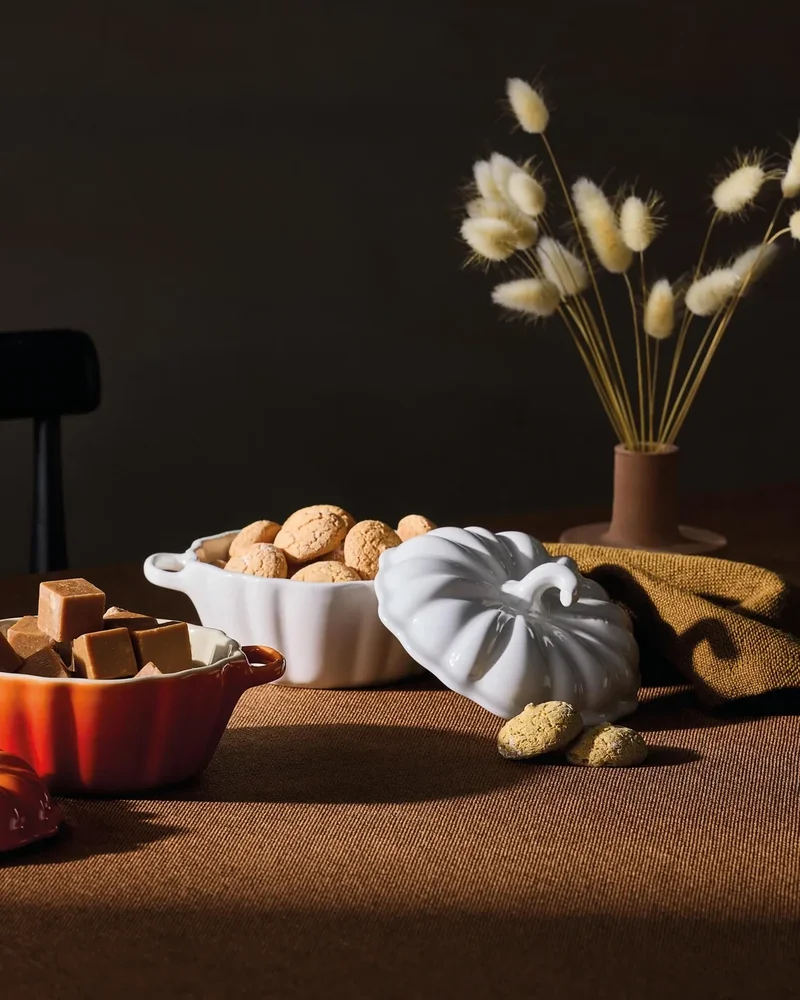 Mini cocottes en céramique en forme de citrouille blanche et orange sur une table d'automne