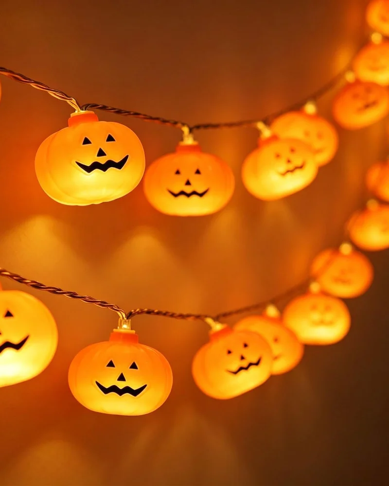 Guirlande lumineuse de petites citrouilles orange au visage souriant dans une ambiance chaleureuse