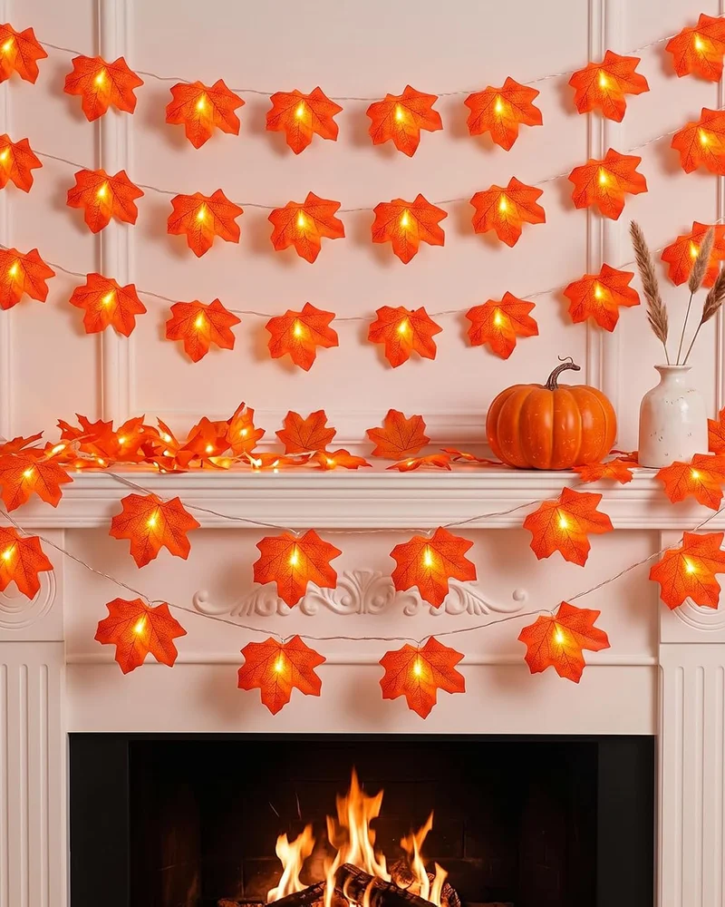 Guirlandes lumineuses de feuilles d'érable orange au-dessus d'une cheminée avec citrouille