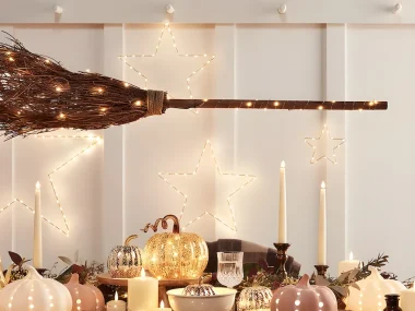 décoration d'Halloween chic avec balai lumineux, étoiles LED et citrouilles en céramique rose sur une table