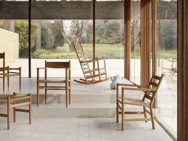 Rocking chair en chêne au dossier en échelle et chaises en bois dans une pièce aux grandes baies vitrées