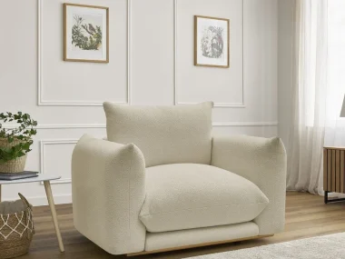 Grand fauteuil en bouclette beige aux lignes arrondies dans un salon blanc à moulures