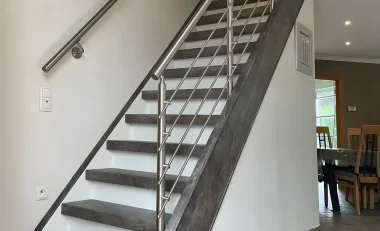 Escalier droit rénové avec marches grises effet pierre, contremarches blanches et garde-corps inox