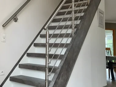 Escalier droit rénové avec marches grises effet pierre, contremarches blanches et garde-corps inox