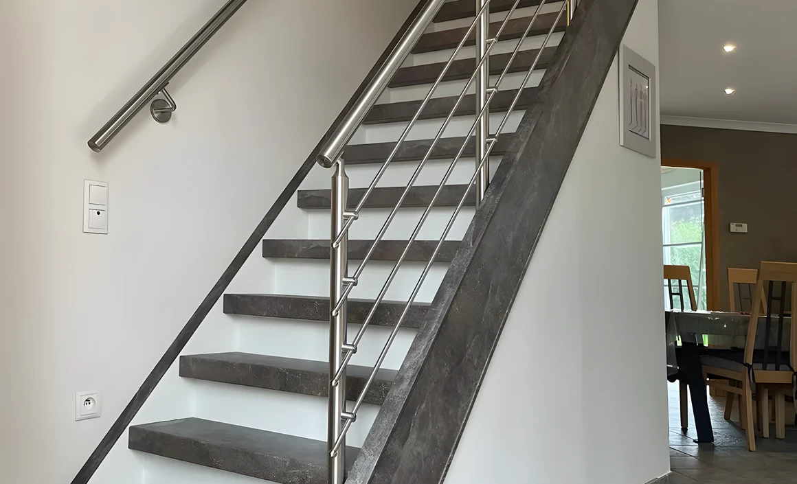 Escalier droit rénové avec marches grises effet pierre, contremarches blanches et garde-corps inox