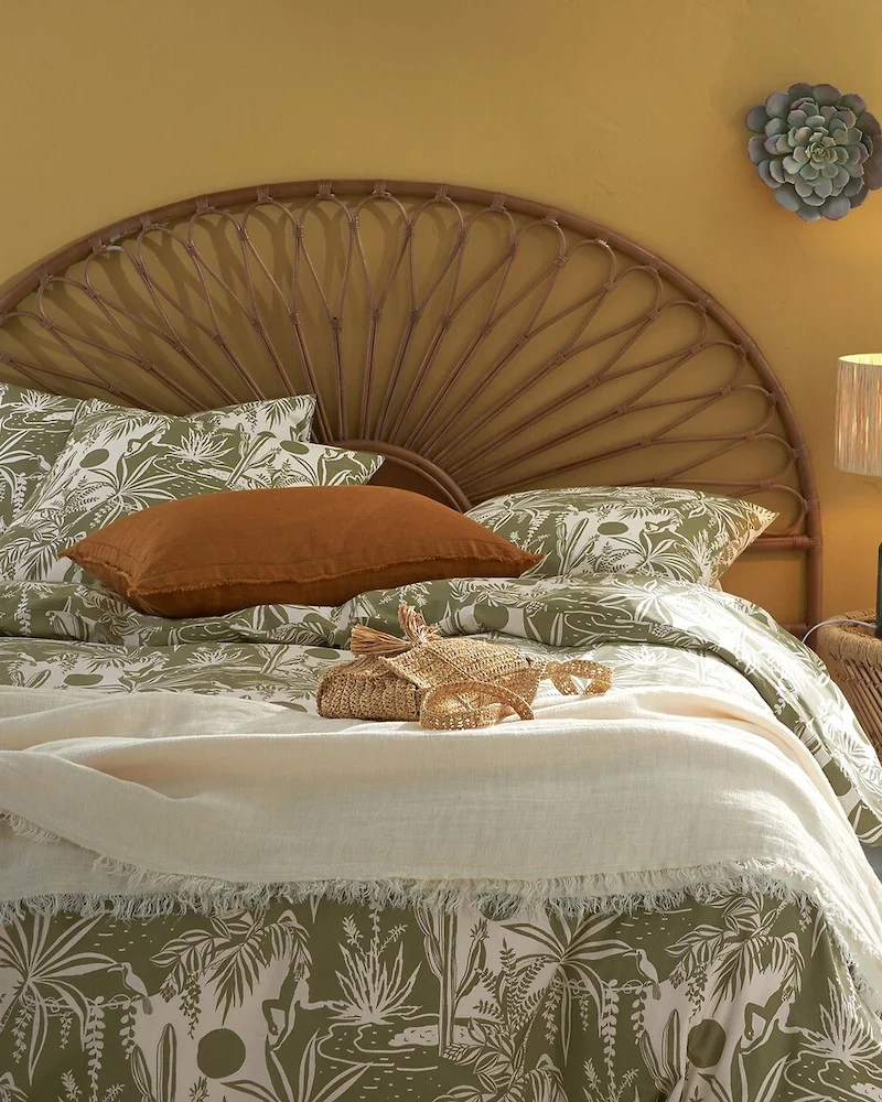 Tête de lit Tio en canne de rotin en forme de demi-lune rayonnante dans une chambre aux murs jaunes