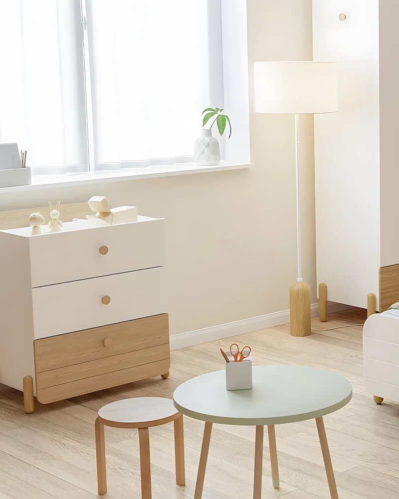 Petite commode bébé moderne blanche avec tiroir inférieur en bois sur pieds dans une chambre claire