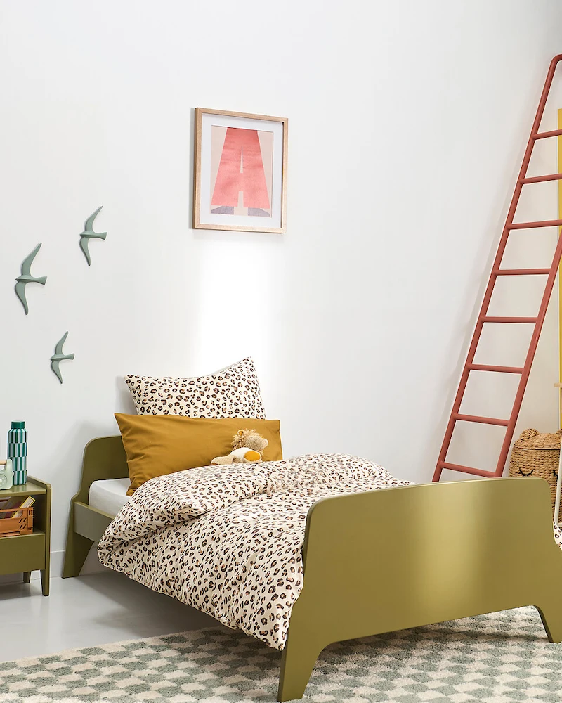 Lit enfant vert kaki aux tête et pied de lit arrondis dans une chambre blanche avec linge léopard
