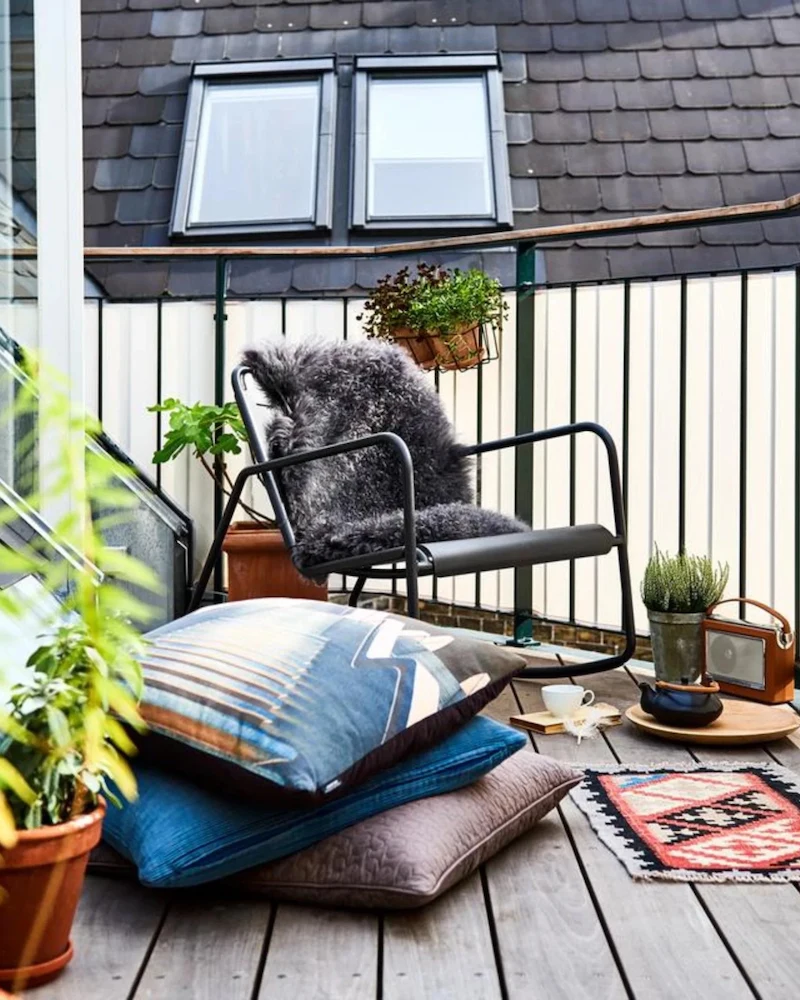 Rocking chair Copenhagen de Cane-Line en aluminium thermolaqué foncé avec plaid sur une terrasse en bois