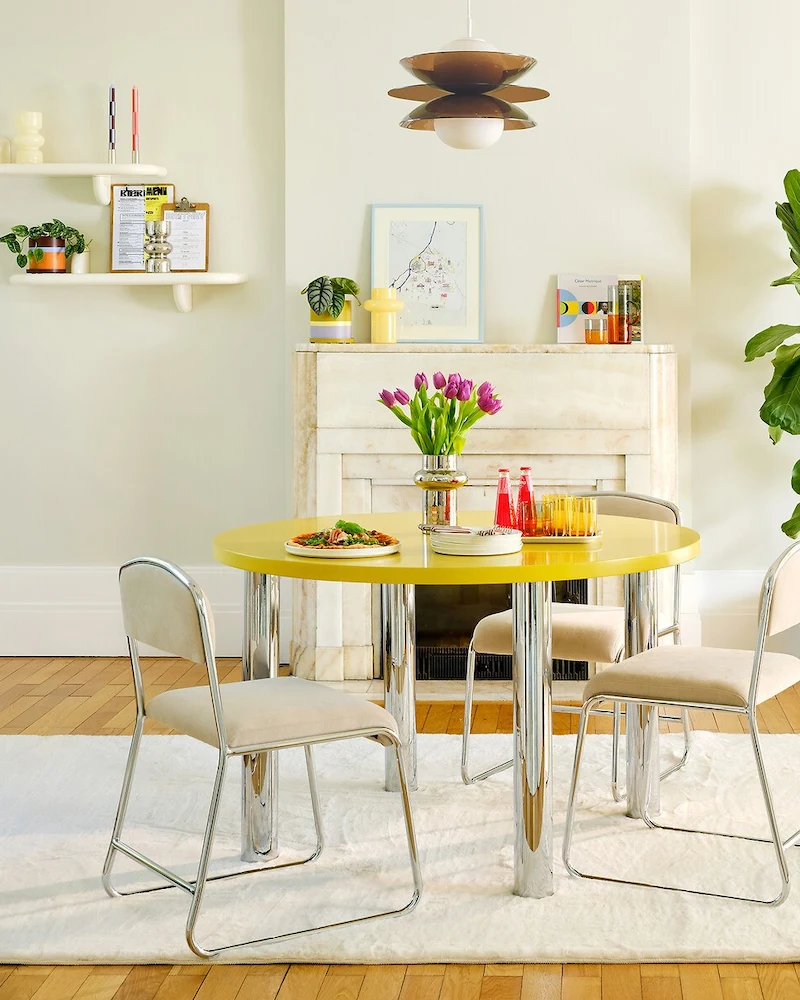 Chaises Celestina à pieds traîneau chromés et tissu beige autour d'une table ronde jaune