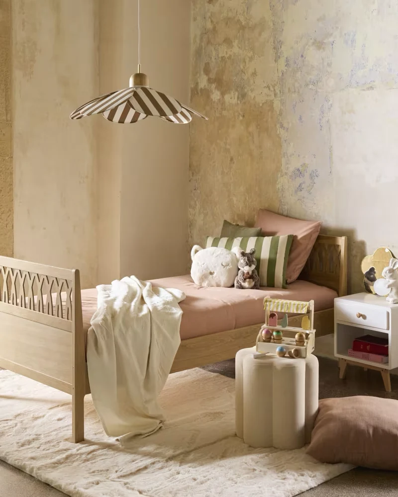Lit enfant à l'aspect bois clair avec pied de lit à motifs en arches dans une chambre aux murs patinés
