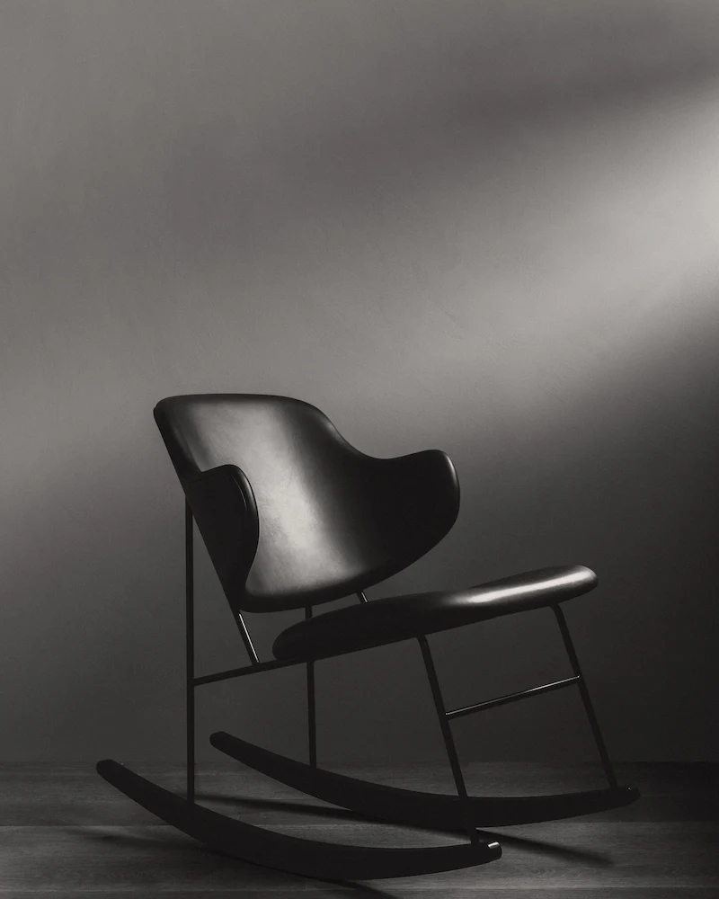 Chaise à bascule Penguin d'Audo noire rembourrée sur cadre en acier dans une ambiance sombre