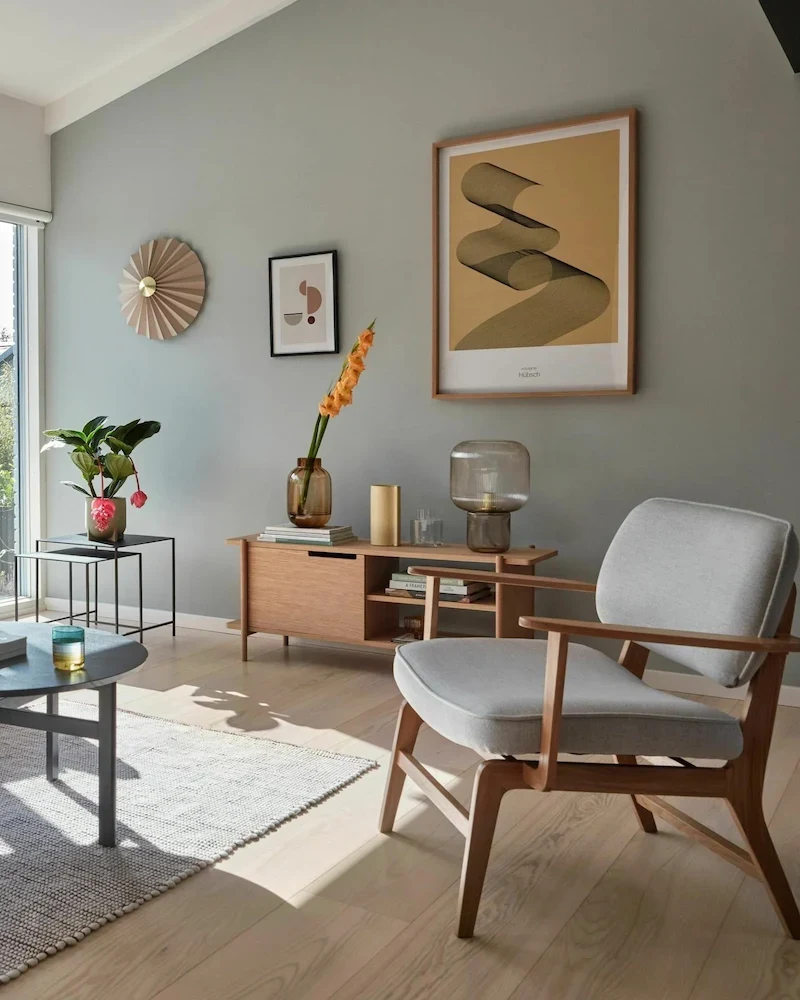 Fauteuil lounge Hübsch en chêne et coussins gris clair dans un salon vert