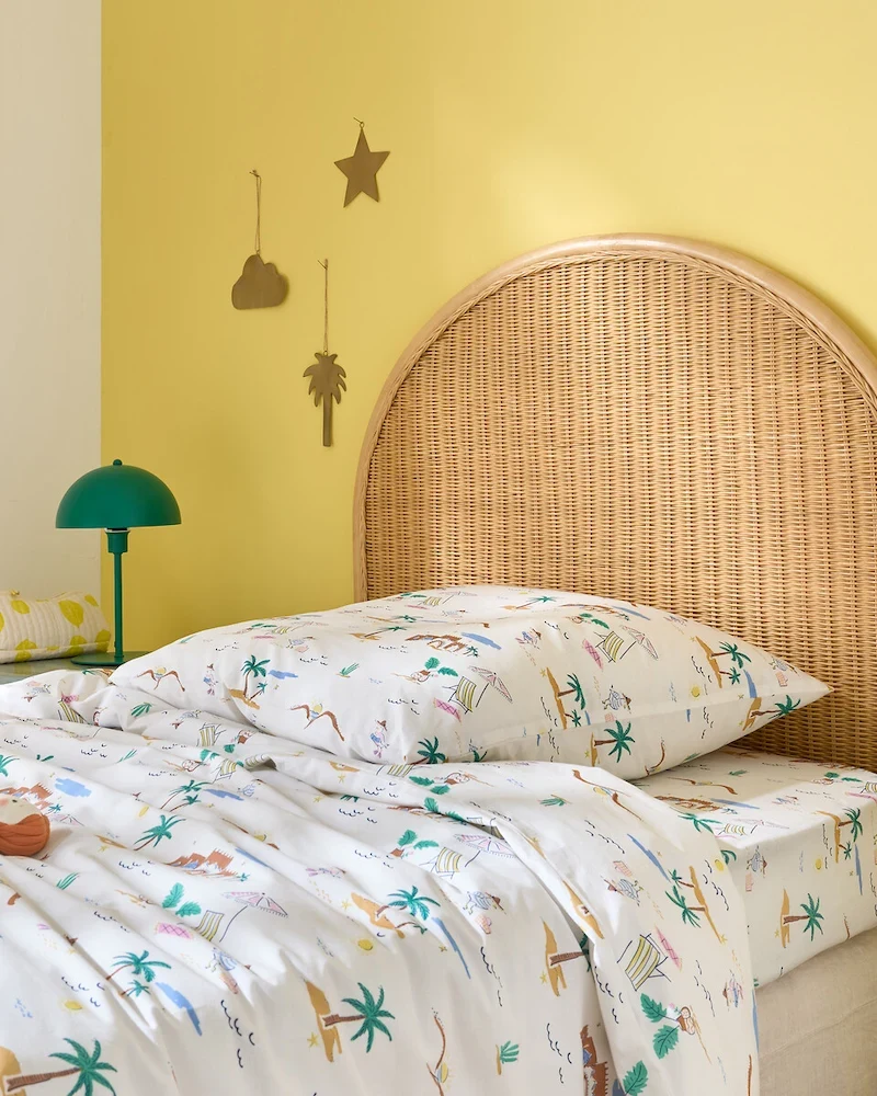 Tête de lit Molly en rotin naturel contre un mur jaune