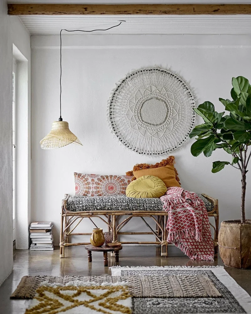 Banc Pammi de Bloomingville en cannage avec coussins dans un salon bohème
