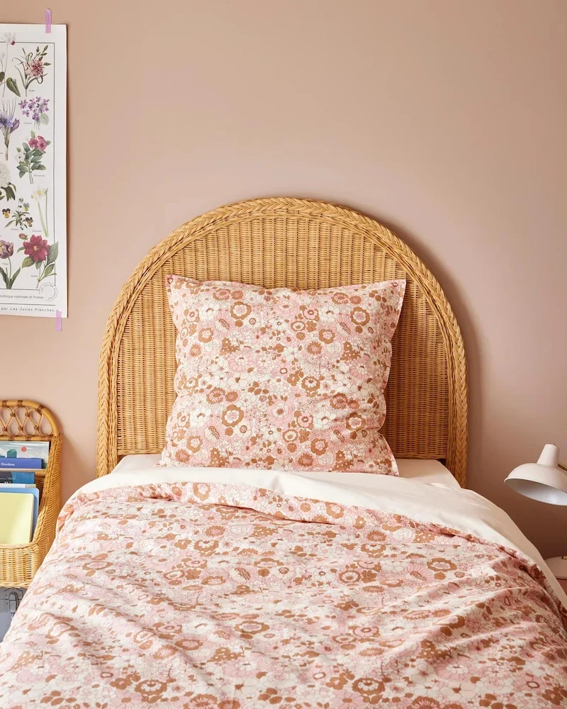 Tête de lit Marcel en rotin miel de Cyrillus derrière un lit à linge fleuri