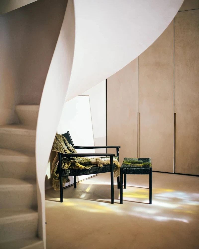 Fauteuil Cullinan de Pomax en manguier noir et jonc de mer tressé près d'un escalier
