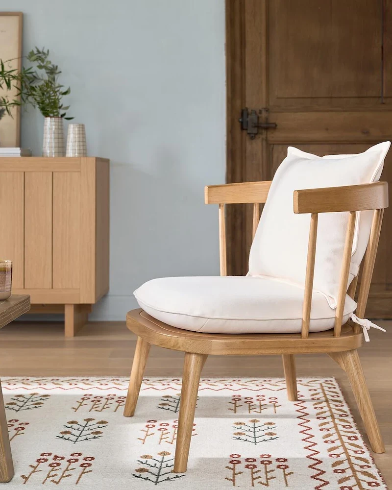 Fauteuil Portman en chêne massif avec coussins beiges dans un salon