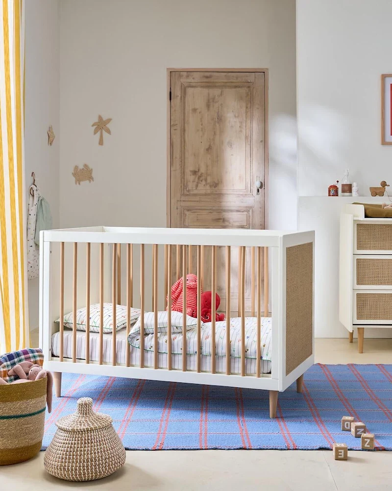 Lit bébé Kaya blanc avec façades en cannage et barreaux en hévéa