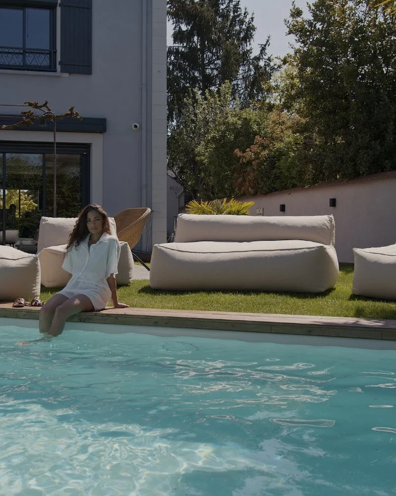 Canapé de jardin modulable Riviera beige aux formes arrondies au bord d'une piscine