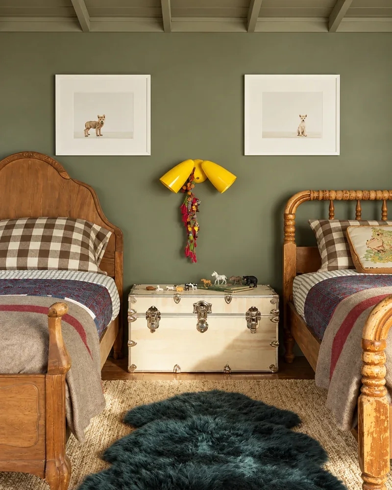 Chambre d'enfant campagne avec deux lits vintage en bois, mur vert kaki et coffre ancien