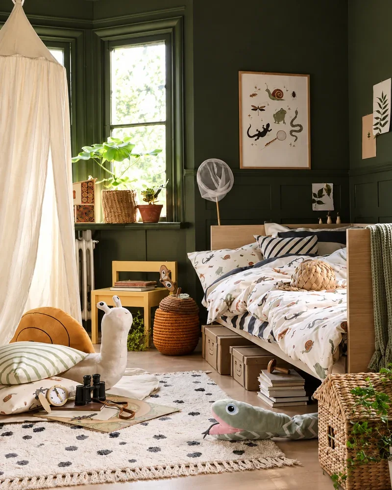 Chambre d'enfant scandinave avec murs vert kaki, lit en bois clair, linge de lit à motifs animaux et accessoires naturels