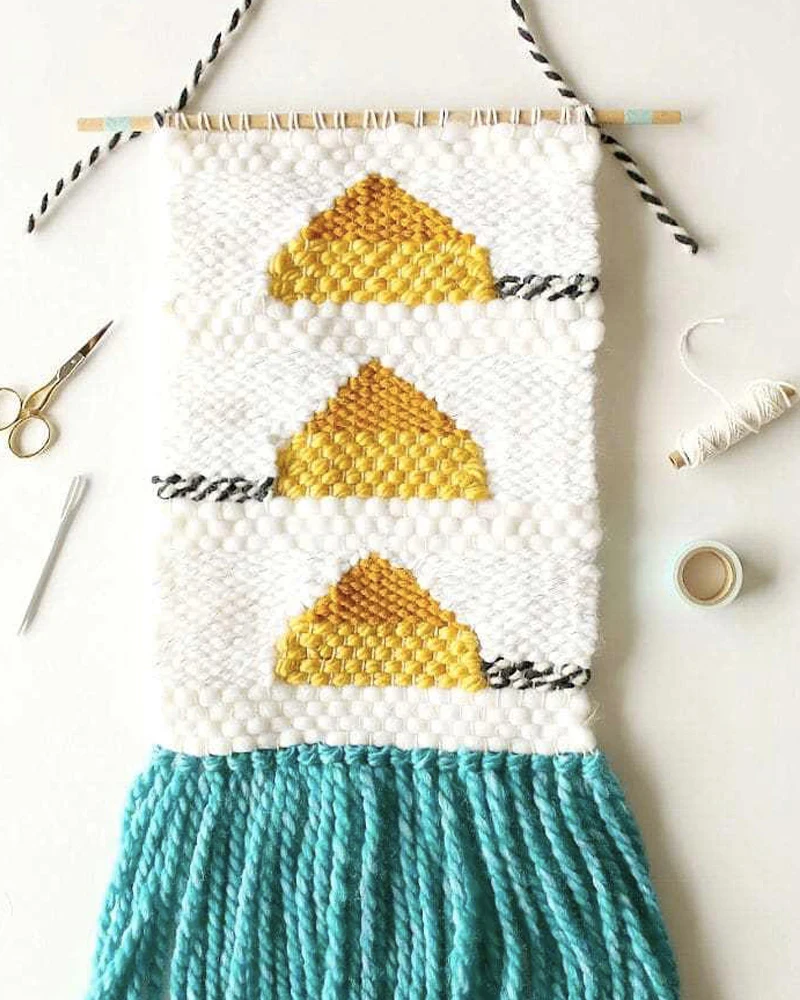 Tissage mural blanc à triangles dorés et frange turquoise