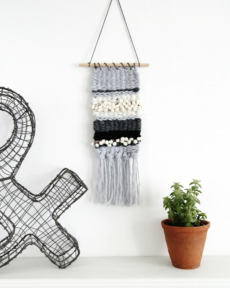 Mini tissage mural aux bandes grises, noires et blanches au-dessus d'une plante