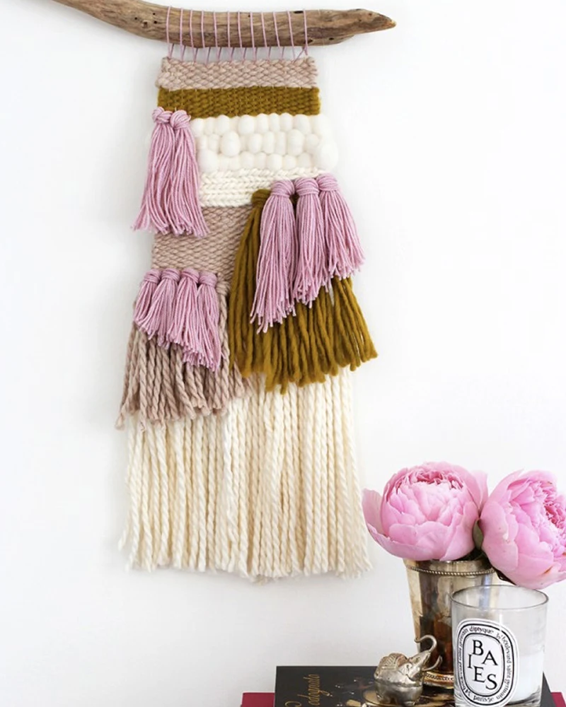 Tissage mural rose, moutarde et crème suspendu à une branche