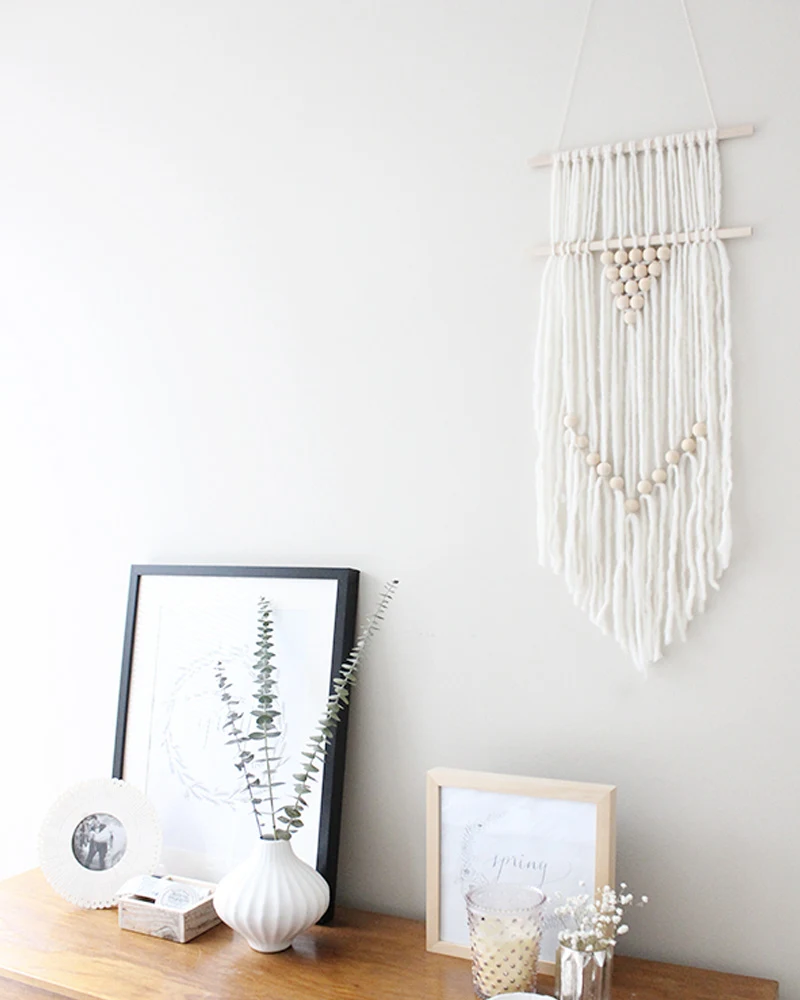 Suspension murale en fils blancs et perles de bois au-dessus d'une console