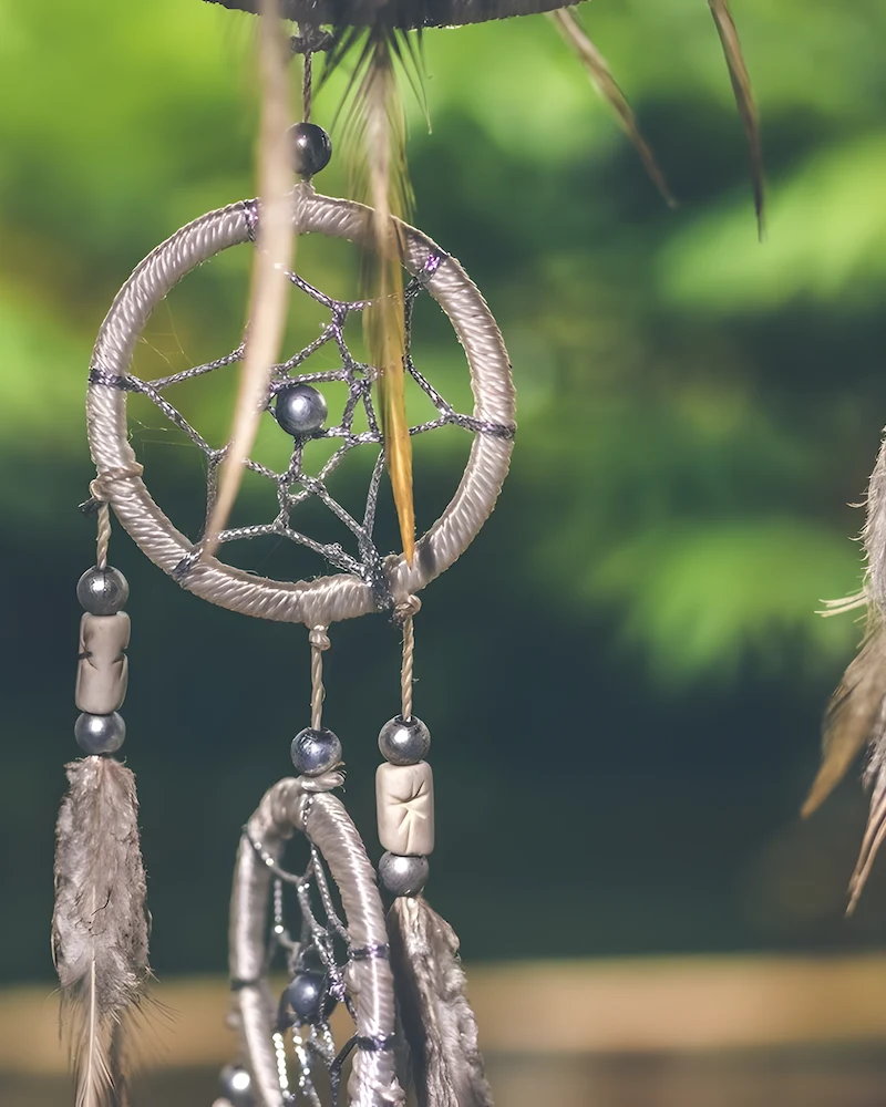 Attrape-rêves tissé suspendu avec plumes et perles dans un jardin