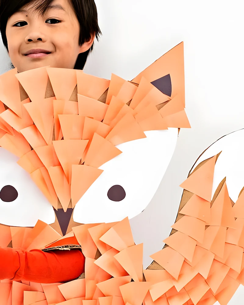 Enfant portant un costume de renard en carton orange