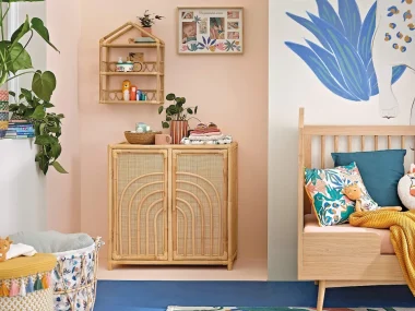 Chambre d'enfant colorée avec cabinet Malaga en rotin à motif arc-en-ciel, banquette en bois et fresque de léopard