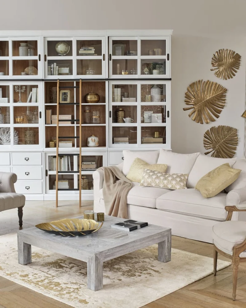 Salon campagne chic avec bibliothèque blanche, canapé écru, fauteuils médaillon et table basse