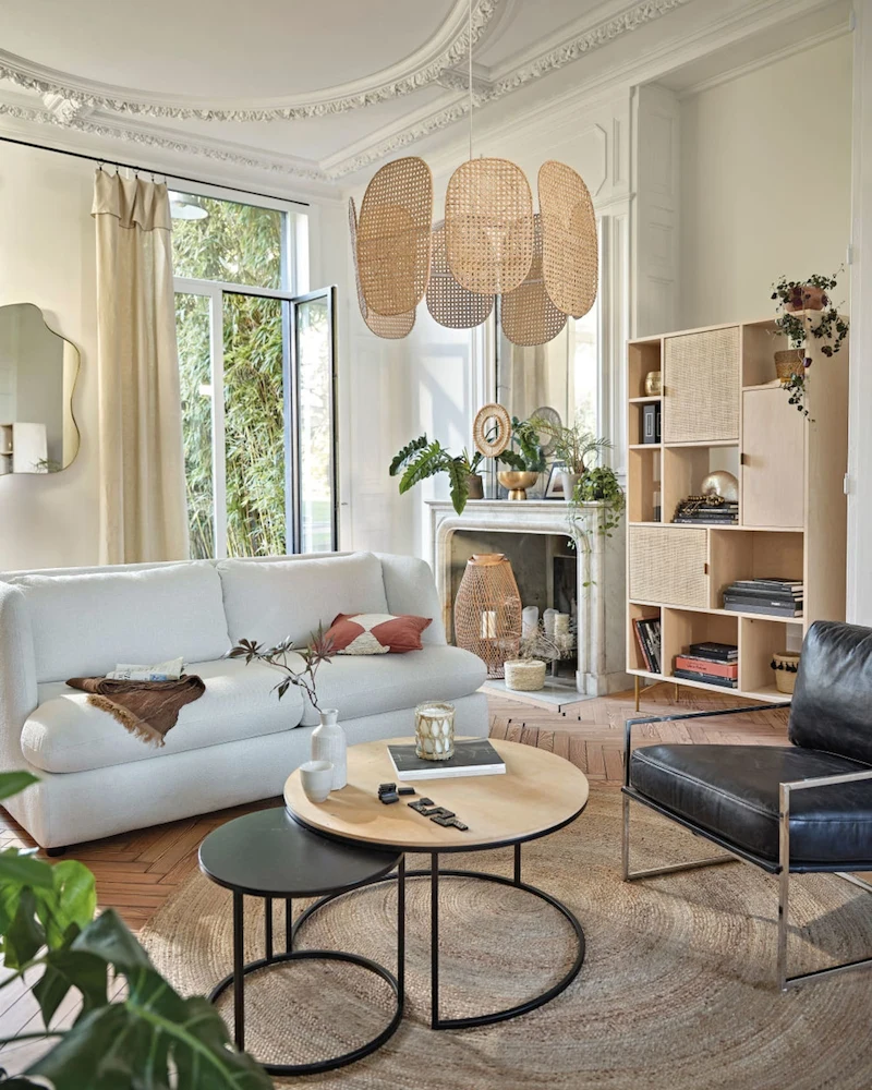 Salon scandinave lumineux avec canapé blanc, tables basses gigognes, bibliothèque en bouleau et suspensions en bois