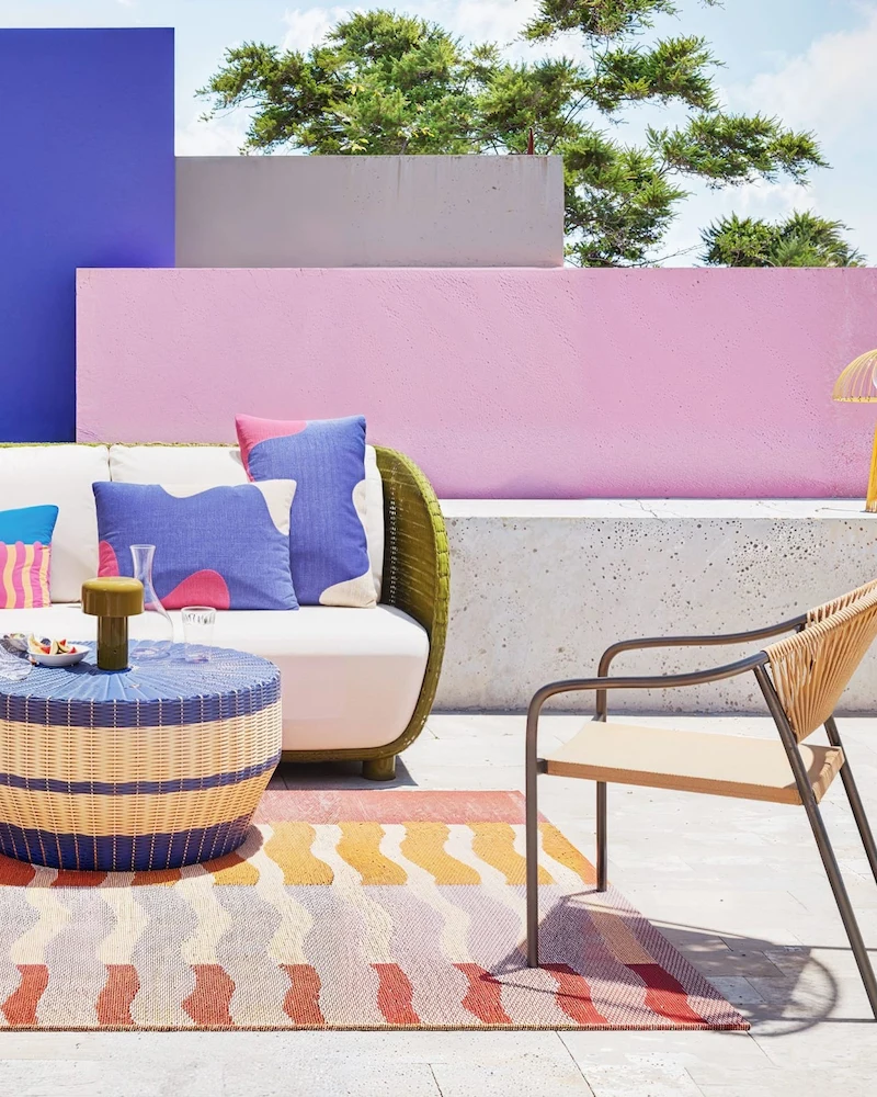 Terrasse colorée avec canapé de jardin en résine tressée vert kaki, fauteuil et tapis rayé