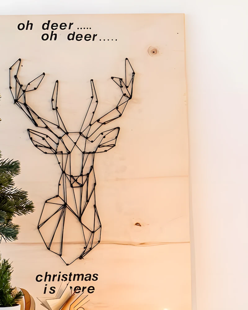 Tête de cerf en clous et ficelle noire sur planche de contreplaqué
