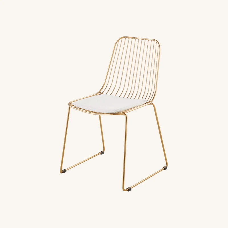 Chaise en acier doré et coussin blanc chez Maisons du Monde